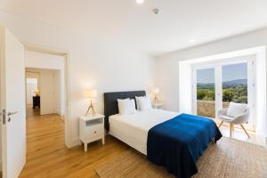 a white bedroom with a large bed and a window at Linden Tree House A and B in Caldelas