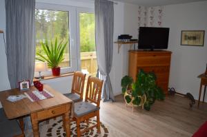 a living room with a wooden table and a desk and a television at Bodasjön in Boda Glasbruk