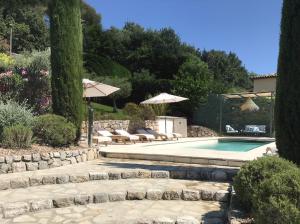 a swimming pool with umbrellas and lounge chairs next to at Bastide Nomade - Charming B&B in Saint-Paul-de-Vence