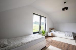 a white bedroom with a bed and a large window at Domki pod Lasem 66 in Trybsz