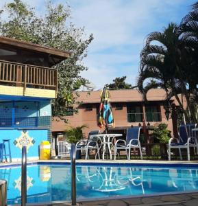 uma piscina de resort com cadeiras e um guarda-sol em Amoreiras Hotel Pousada em Maresias