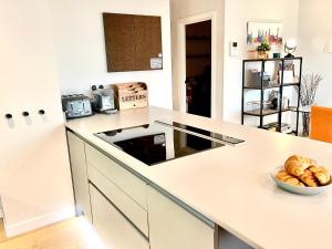 a white kitchen with a bowl of bread on a counter at Apartment Twelve in Shrewsbury