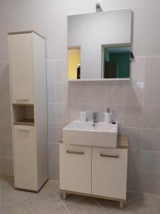 a bathroom with a white sink and a mirror at Apartmani Ljuba in Rogoznica