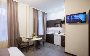 a room with a table and a kitchen with a tv at Khreshchatyk Apart Hotel 911 in Kyiv
