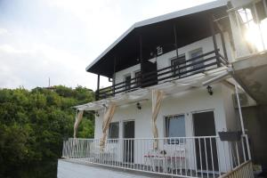 a white house with a balcony and the sun shining at Apartments Villa Naumovi in Star Dojran