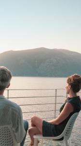 a man and a woman sitting on a ferry looking at the water at Akasha Suite III in Vathi