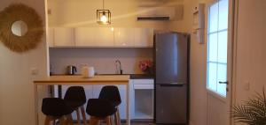 eine Küche mit einem Kühlschrank und einer Theke mit Stühlen in der Unterkunft Petit Cocon in La Croix-Valmer