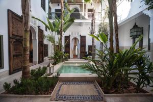 a courtyard with a swimming pool in a building with trees at Riad Jaaneman in Marrakesh