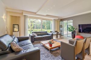 a living room with leather couches and a tv at Vlaeberg Birdhouse in Diksmuide