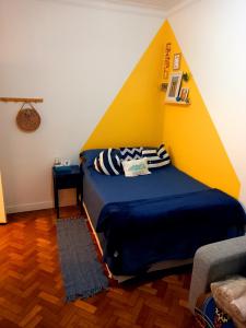 een slaapkamer met een bed met een gele muur bij Cafofo Nice in Rio de Janeiro