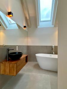 een badkamer met een bad, een wastafel en een raam bij “STADT-LAND-SCHEUNE” - luxuriös in alten Gemäuern in Braunschweig
