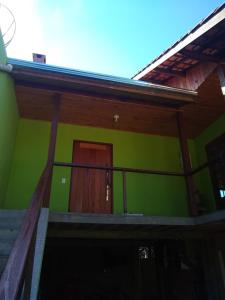 a green building with stairs and a door at Recanto do Loriano in Monte Verde