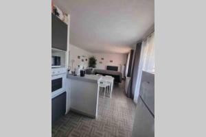 ル・ボーセにあるBel appartement avec balcon et parking privéの白い冷蔵庫とテーブルのあるキッチン +12枚の写真