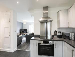 a kitchen with white cabinets and a stove top oven at 19 Parc Delfryn in Brynteg