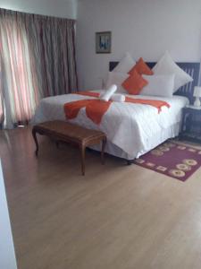 Schlafzimmer mit einem Bett mit weißen und orangefarbenen Kissen in der Unterkunft Ezamampondo Guest House in King Williamʼs Town
