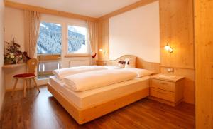 sypialnia z dużym łóżkiem przed oknem w obiekcie Apartments Antines w mieście Selva di Val Gardena