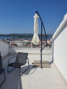 een witte parasol en een stoel op een balkon bij Franko & Šimun Apartment in Šibenik