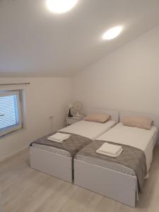 een witte slaapkamer met 2 bedden en een raam bij Franko & Šimun Apartment in Šibenik