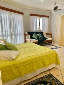 Un dormitorio con una gran cama amarilla y un sofá en Residencial Nápole, en Torres