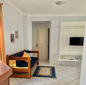 a living room with a couch and a tv on a wall at Residencial Nápole in Torres