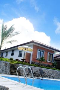 una casa con piscina y una casa con sombrilla en Osmond Villa Resort, en Lembang