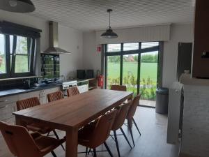 uma cozinha com uma grande mesa de madeira e cadeiras em vakantiehuis zoetendaal em Reningelst