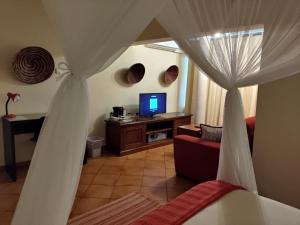 a living room with a bed and a television at Sundown Guest House Maputo in Maputo