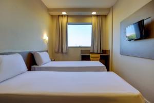 a hotel room with two beds and a television at Transamerica FIT Lucas do Rio Verde in Lucas do Rio Verde +16 photos