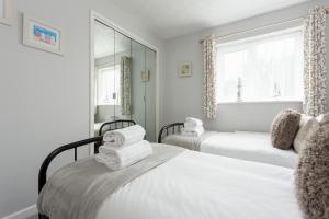 een witte slaapkamer met 2 bedden en een raam bij Solstice in Poole