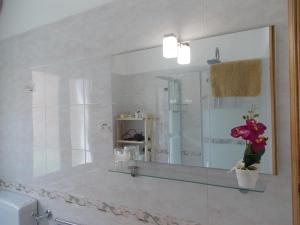 a bathroom with a mirror and a vase of flowers at Villa Il Melograno in Taormina +44 photos