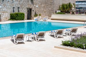 a swimming pool with chaise lounge chairs and a swimming pool at Hotel Lapad in Dubrovnik