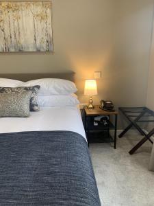 een slaapkamer met een bed en een tafel met een lamp bij The Cedar Country Hotel in Bellway