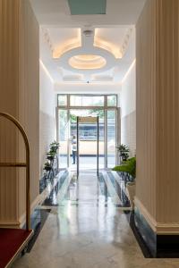 a lobby with a hallway with plants and a chandelier at Hotel Majestic in Casablanca