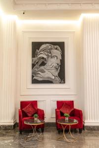a room with two red chairs and a painting on the wall at Hotel Majestic in Casablanca