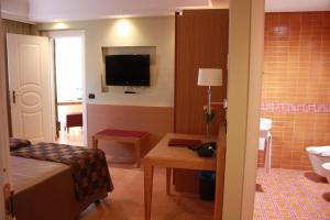 a room with a bed and a bathroom with a television at Artemis Hotel in Cefalù