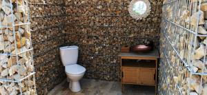 a bathroom with a toilet and a wall of logs at Luna Glamping in Tuzla