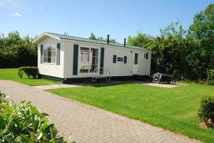 a small white house in a yard with a lawn at Minicamping De Visser in Zoutelande