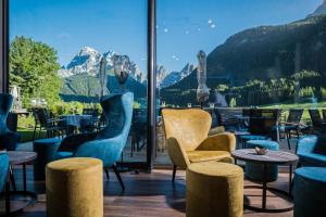 a room with chairs and tables and a large window at Alpenwellnesshotel St. Veit in Sesto