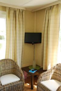 a living room with two chairs and a flat screen tv at Minicamping De Visser in Zoutelande
