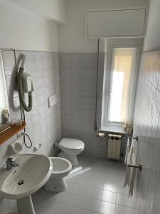 a white bathroom with a sink and a toilet at Hotel Stazione del Sole in Albenga