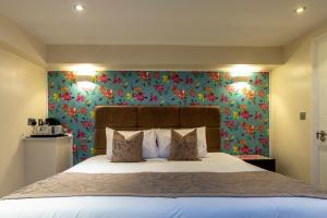 um quarto com uma cama grande e papel de parede floral em Hotel Shepherds Bush London em Londres