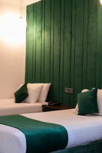 two beds in a room with a green wall at Hotel Majestic in Casablanca