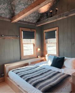 1 cama grande en un dormitorio con 2 ventanas en Stonehill's Farmhouse, en Accord