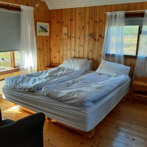 two beds in a room with wooden walls at Hagi 1 Guesthouse in Aðaldalur