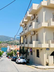 um edifício alto e branco com carros estacionados na rua em Argostoli Hotel em Argostoli