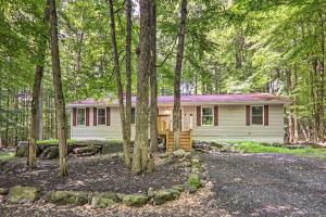 una pequeña casa blanca en el bosque con árboles en Sunroom, Fire Pit and Sauna Lake Locust Village Gem, en Pocono Lake