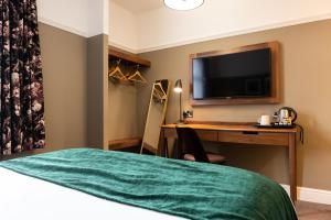 a hotel room with a desk and a television at The Oatlands Chaser by Innkeeper's Collection in Weybridge