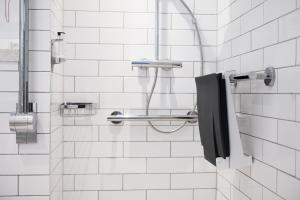 a bathroom with a shower with a black towel at The Oatlands Chaser by Innkeeper's Collection in Weybridge
