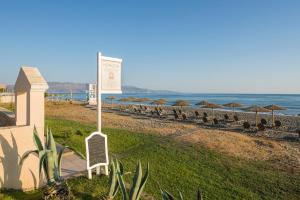 einen Strand mit Liegestühlen und Sonnenschirmen und dem Meer in der Unterkunft Hotel Caretta Beach in Gerani Chania