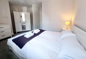 a bedroom with a large white bed and a mirror at Modern Maisonette 2 Bedrooms Newly Renovated in Bournemouth